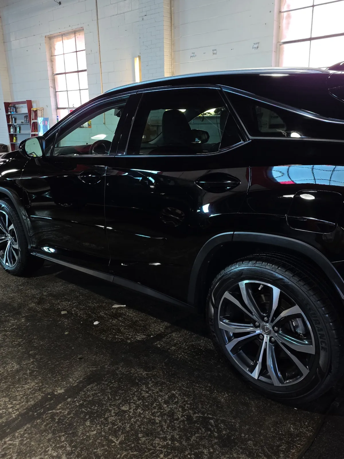 Glossy black Lexus RX reflecting the shop windows